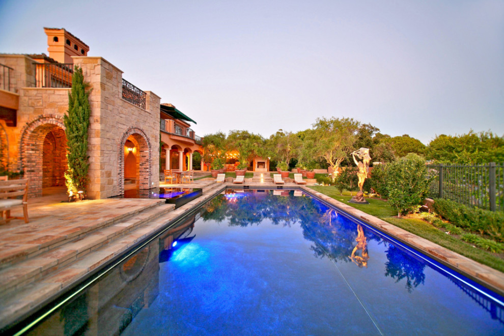 Diseño de piscina mediterránea extra grande a medida en patio trasero con adoquines de piedra natural
