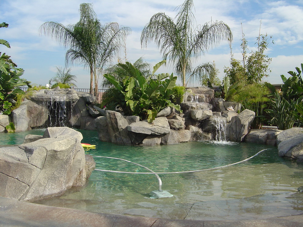 Immagine di una grande piscina fuori terra personalizzata dietro casa con fontane e cemento stampato