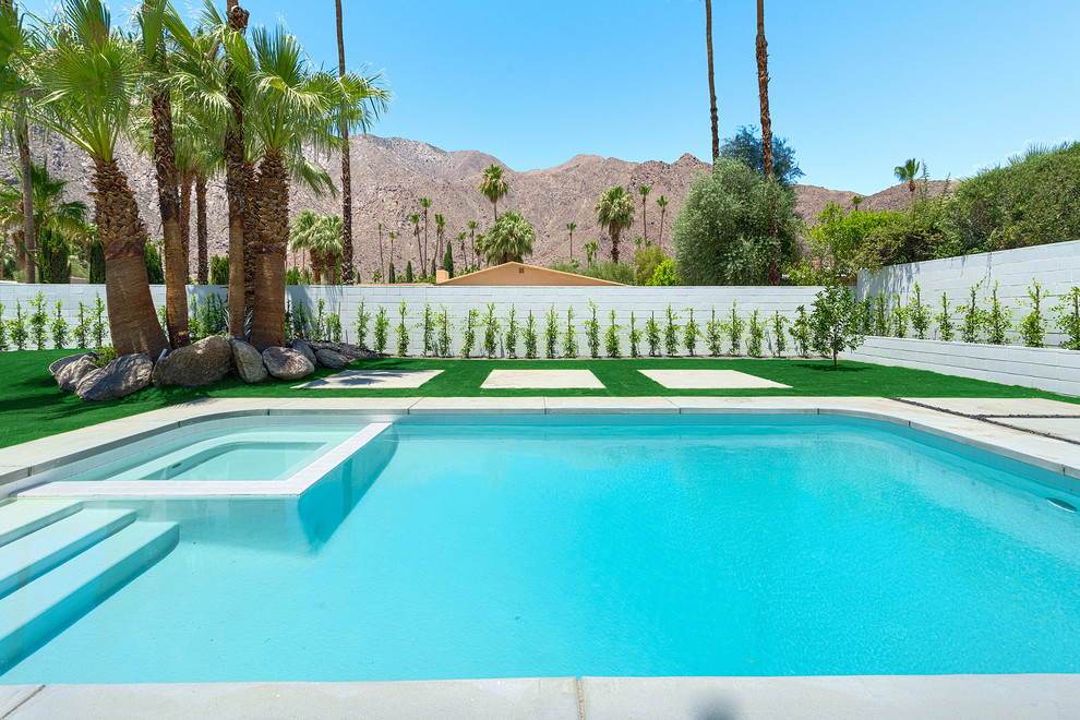 Imagen de piscinas y jacuzzis retro grandes rectangulares en patio trasero con losas de hormigón