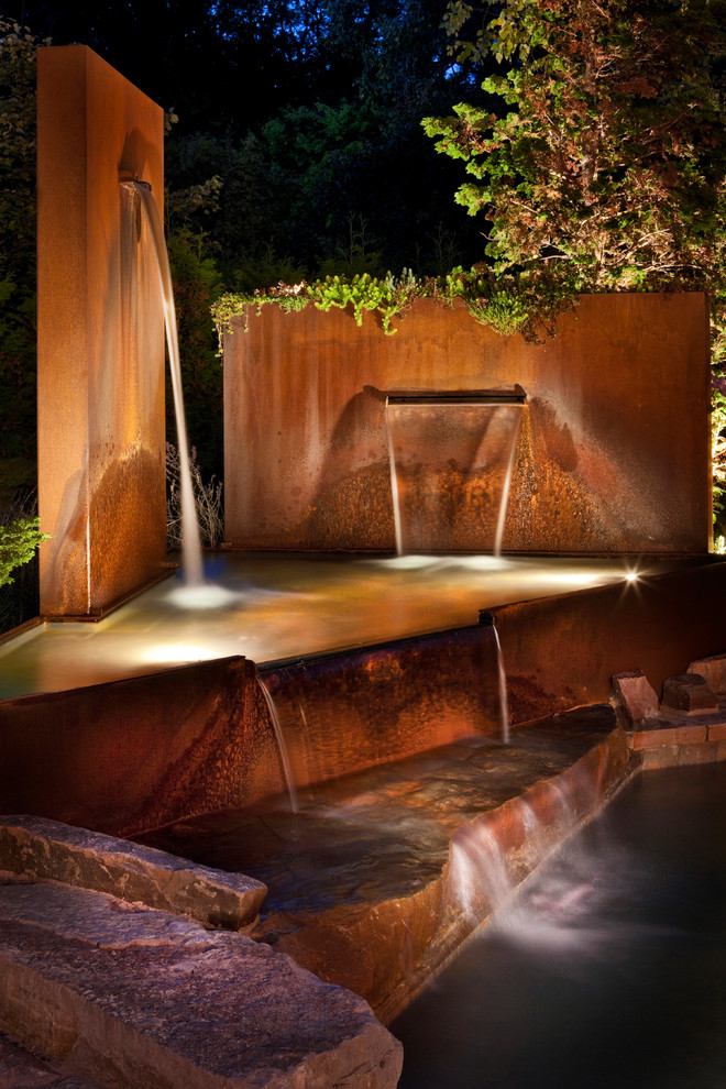 Diseño de piscina con fuente elevada minimalista de tamaño medio a medida en patio trasero con adoquines de piedra natural