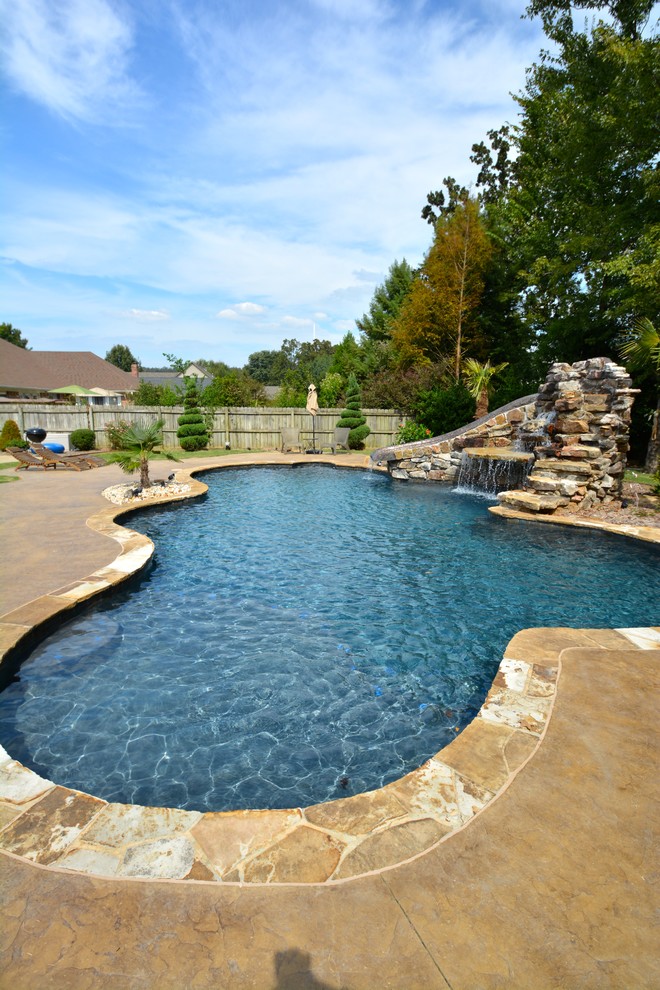 Diseño de piscina con tobogán alargada rústica de tamaño medio a medida en patio trasero con adoquines de piedra natural