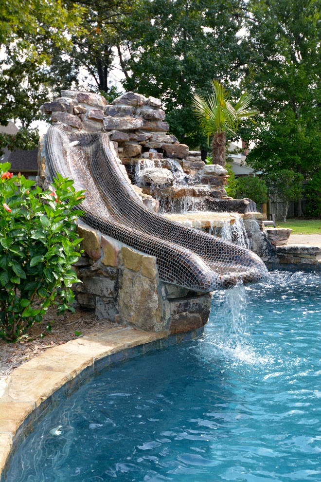 Imagen de piscina con tobogán alargada rústica de tamaño medio a medida en patio trasero con adoquines de piedra natural
