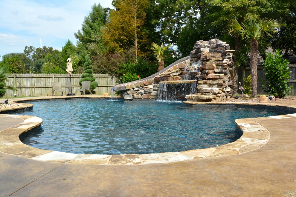 Imagen de piscina con tobogán alargada rural de tamaño medio a medida en patio trasero con adoquines de piedra natural