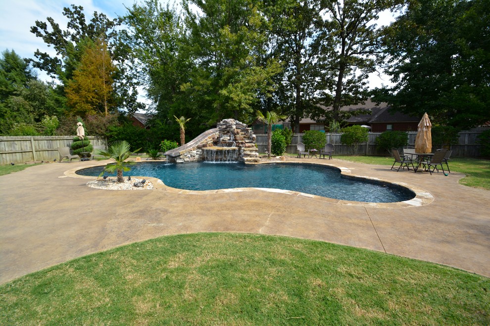 Ejemplo de piscina con tobogán alargada rural de tamaño medio a medida en patio trasero con adoquines de piedra natural
