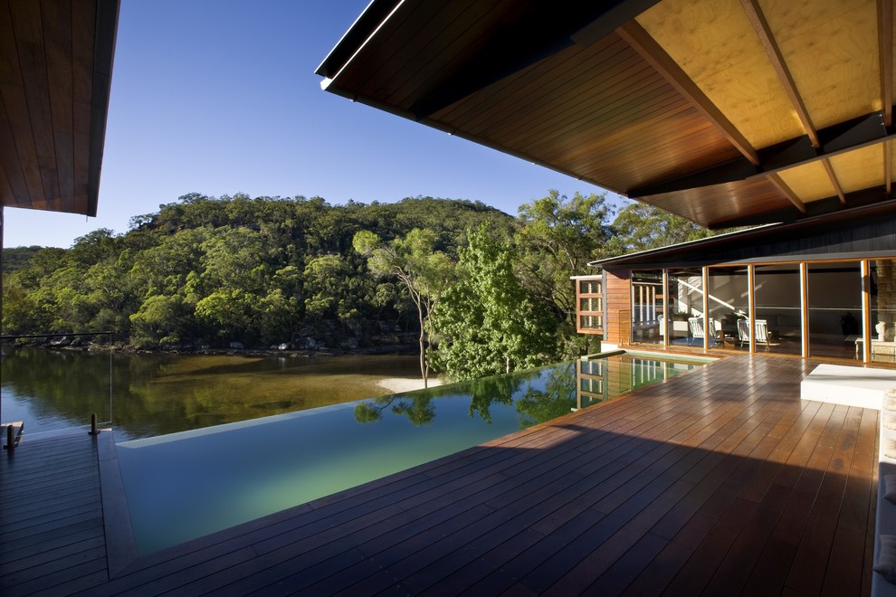 Idées déco pour une grande piscine à débordement contemporaine rectangle avec une terrasse en bois.