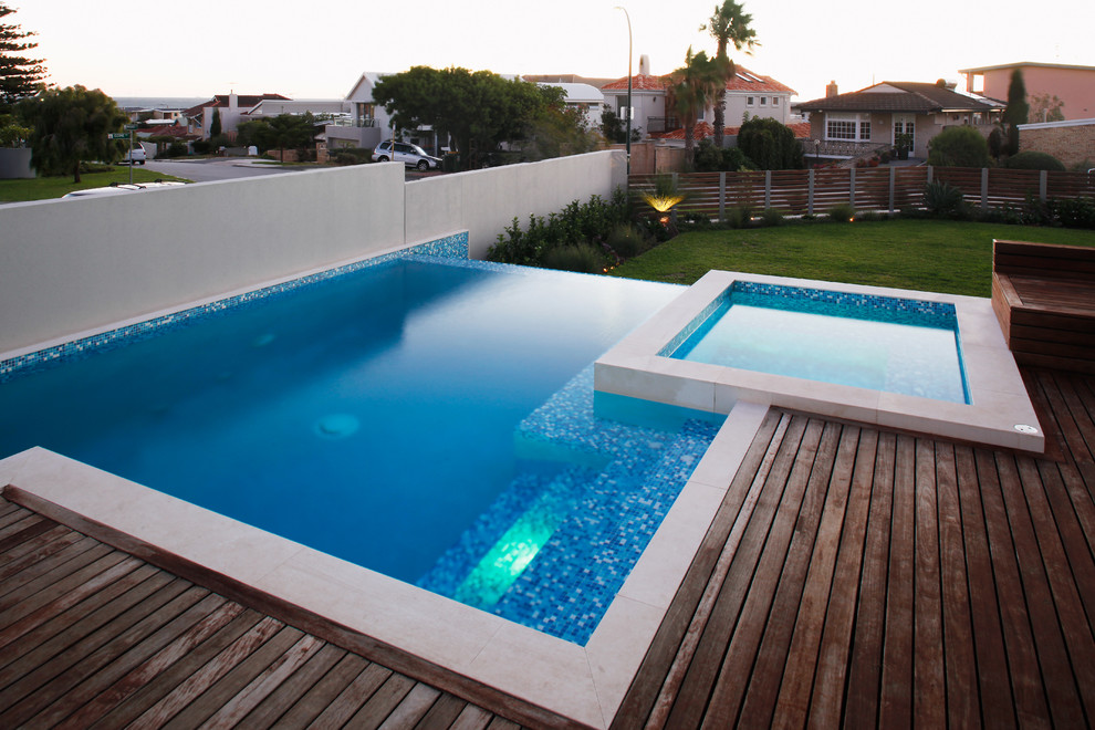 This is an example of a large contemporary side custom shaped above ground swimming pool in Perth with a water feature and decking.
