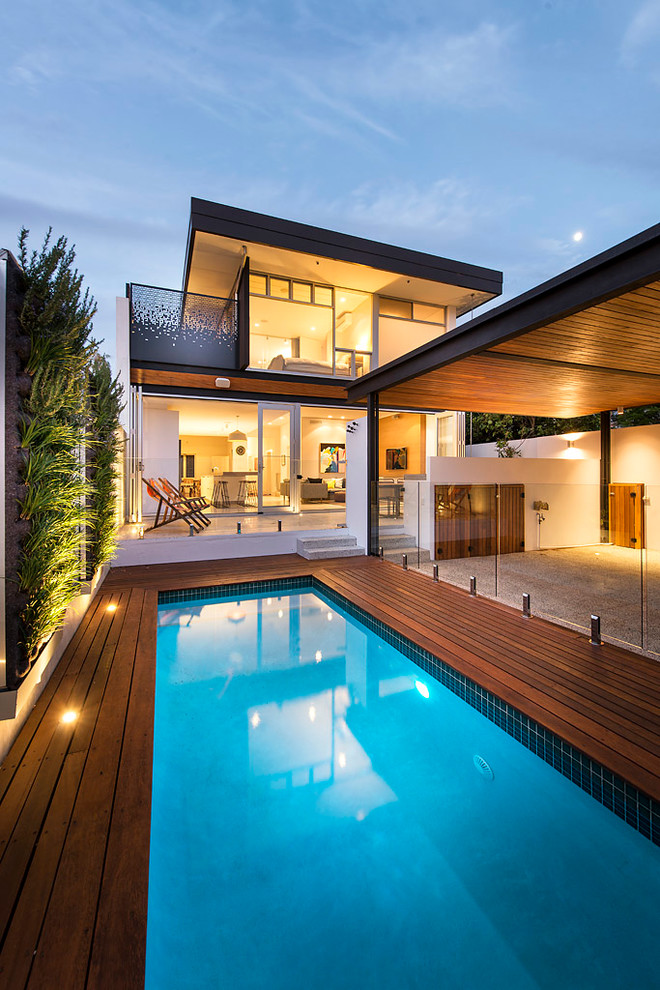 Diseño de piscina alargada contemporánea pequeña rectangular en patio trasero con entablado