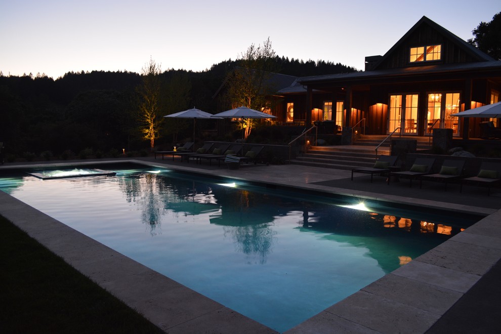 Modelo de piscinas y jacuzzis campestres grandes rectangulares en patio trasero con losas de hormigón