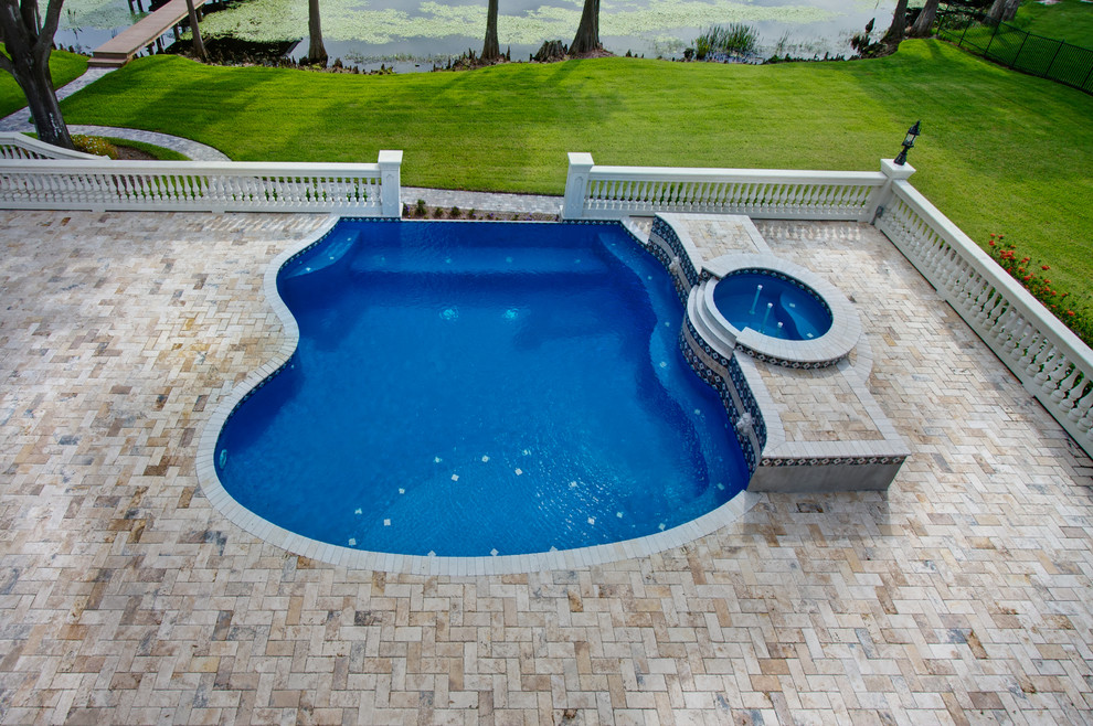 Imagen de piscina natural de tamaño medio a medida en patio trasero con adoquines de piedra natural