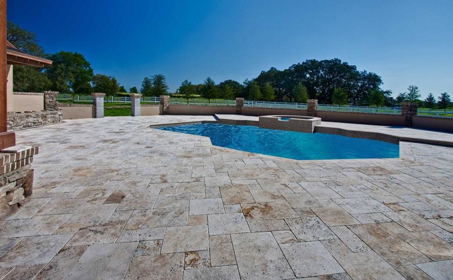 Foto de piscinas y jacuzzis alargados grandes a medida en patio trasero con adoquines de piedra natural