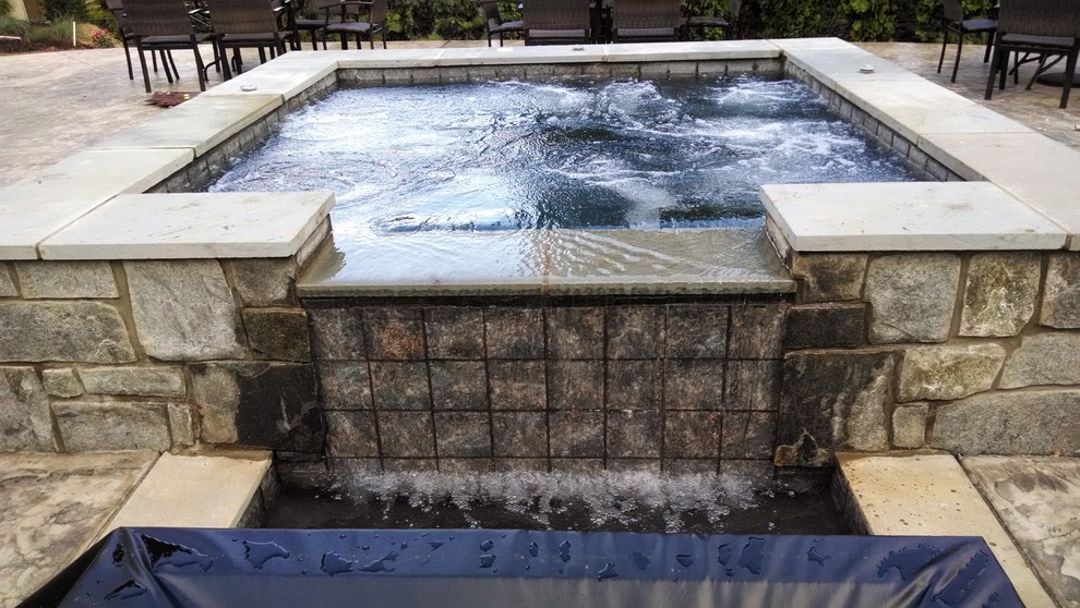Photo of a medium sized classic back custom shaped swimming pool in Other with a water feature and natural stone paving.