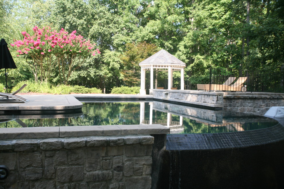 Large minimalist backyard stone and l-shaped natural pool house photo in Other