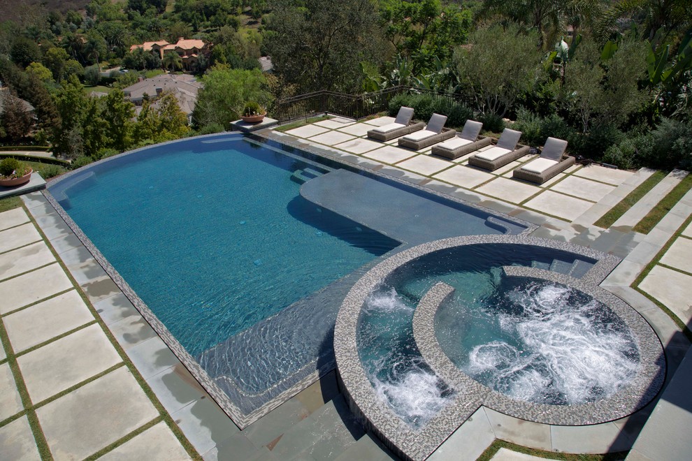 Immagine di una grande piscina a sfioro infinito minimalista personalizzata dietro casa