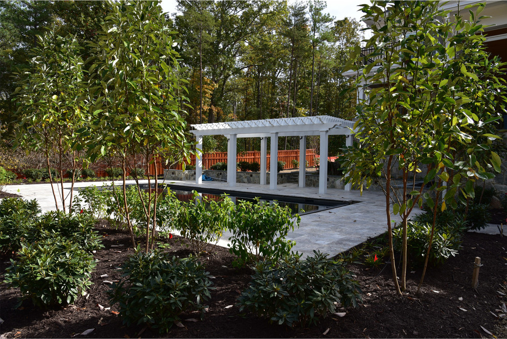 Imagen de piscina alargada clásica de tamaño medio rectangular en patio trasero con adoquines de piedra natural