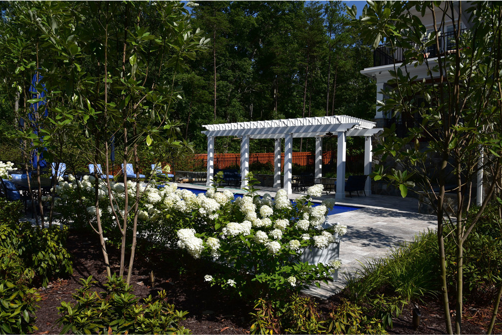 Ejemplo de piscina alargada clásica de tamaño medio rectangular en patio trasero con adoquines de piedra natural