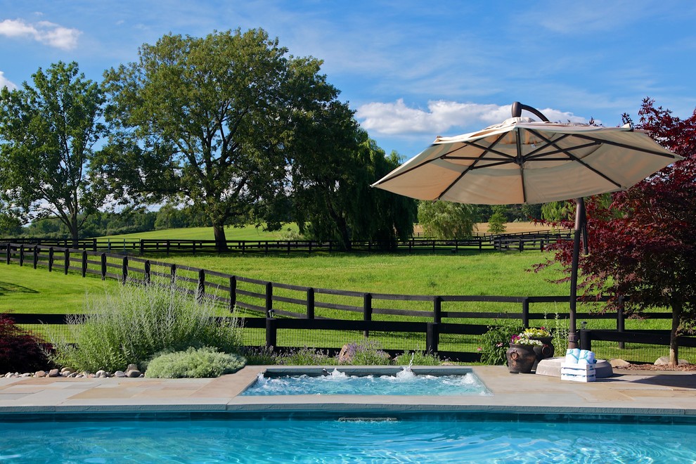 Immagine di una piscina monocorsia country rettangolare di medie dimensioni e dietro casa con una vasca idromassaggio e pavimentazioni in pietra naturale