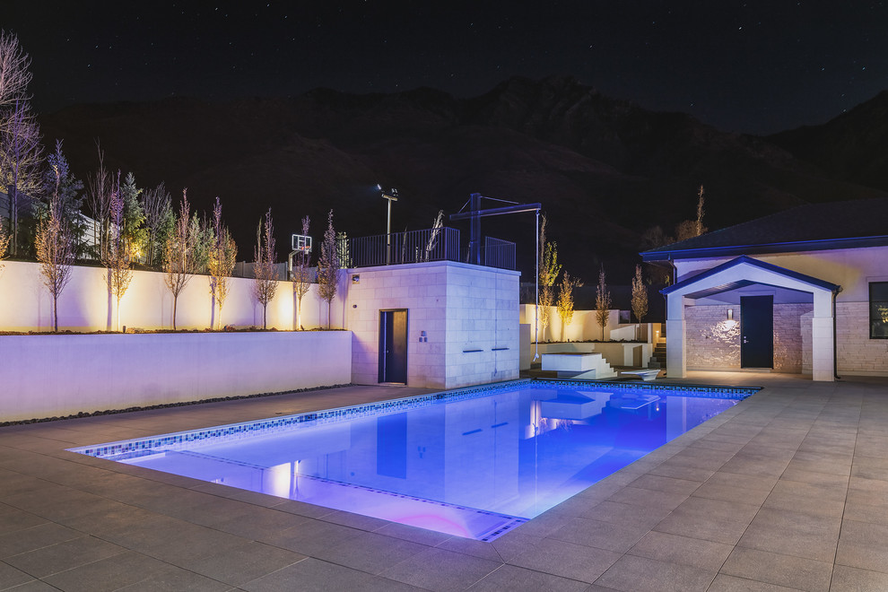 Foto de piscina alargada contemporánea grande rectangular en patio trasero con suelo de baldosas