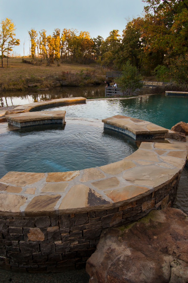 Idée de décoration pour une piscine arrière champêtre de taille moyenne et ronde avec un bain bouillonnant et des pavés en pierre naturelle.