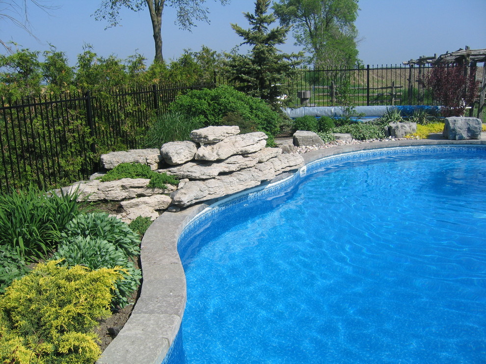 Modelo de piscina con fuente alargada tradicional de tamaño medio a medida en patio trasero con adoquines de hormigón