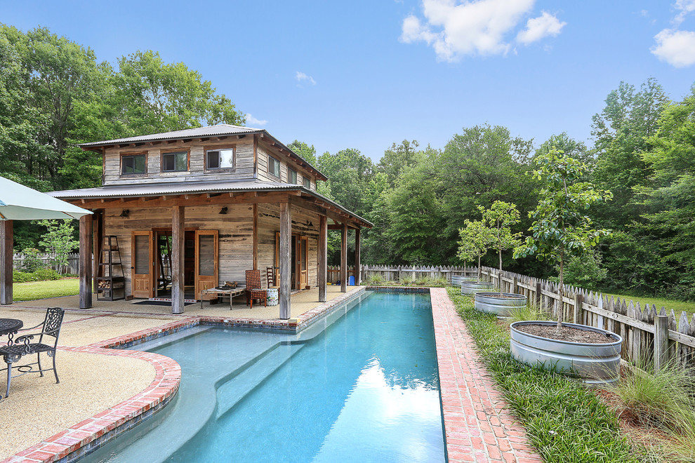 Modelo de casa de la piscina y piscina alargada de estilo de casa de campo grande rectangular en patio trasero con adoquines de ladrillo
