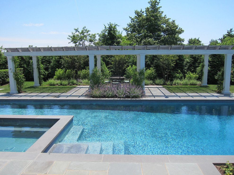 Immagine di una piscina chic personalizzata di medie dimensioni e dietro casa con una vasca idromassaggio e pavimentazioni in pietra naturale