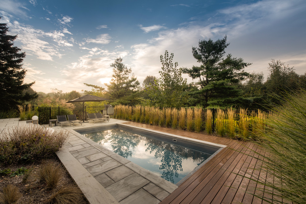 Ejemplo de piscina de estilo de casa de campo rectangular en patio trasero con entablado