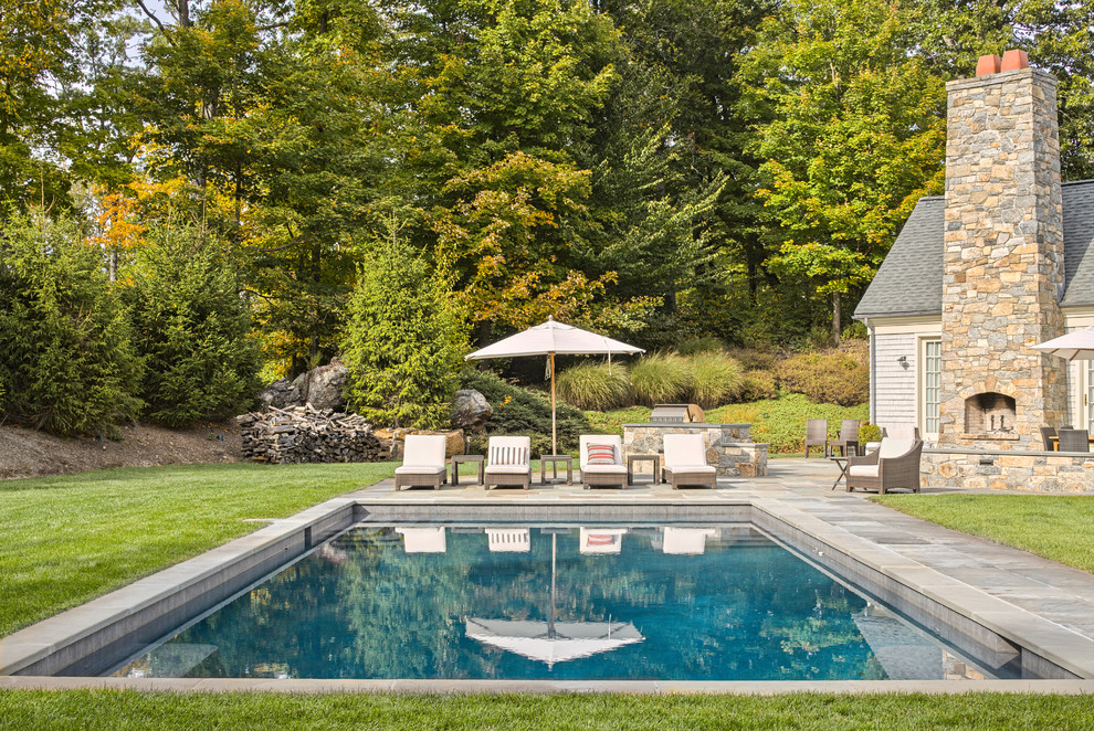 Пример оригинального дизайна: большой прямоугольный, спортивный бассейн на заднем дворе в классическом стиле с покрытием из каменной брусчатки и зоной барбекю