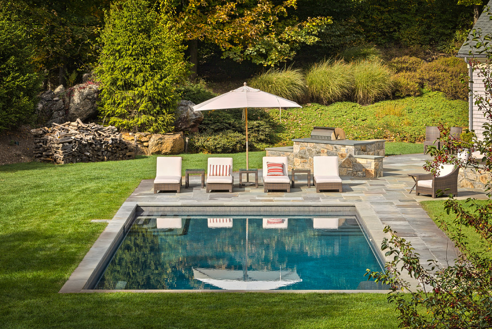 Modelo de casa de la piscina y piscina tradicional grande rectangular en patio trasero con adoquines de piedra natural
