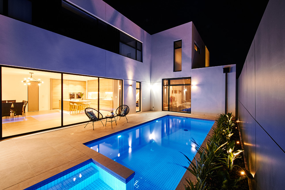 Foto de casa de la piscina y piscina infinita actual grande a medida en patio trasero con adoquines de hormigón