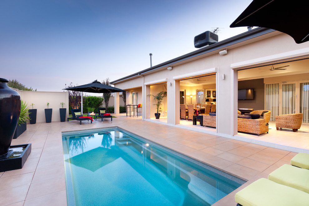 Modelo de piscina alargada contemporánea rectangular en patio con suelo de baldosas