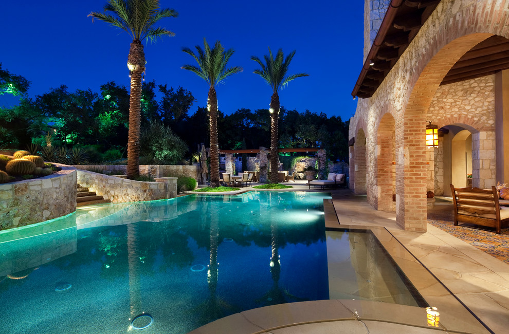 Imagen de piscina infinita mediterránea extra grande a medida en patio trasero con adoquines de piedra natural