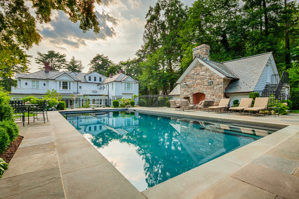 Foto di una grande piscina monocorsia chic rettangolare dietro casa con una vasca idromassaggio e pavimentazioni in pietra naturale
