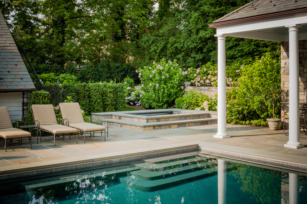 Idee per una grande piscina monocorsia classica rettangolare dietro casa con una vasca idromassaggio e pavimentazioni in pietra naturale