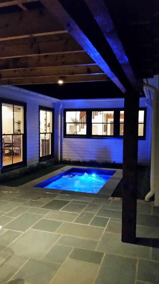 Cette image montre une piscine design rectangle avec un point d'eau, une cour et des pavés en pierre naturelle.
