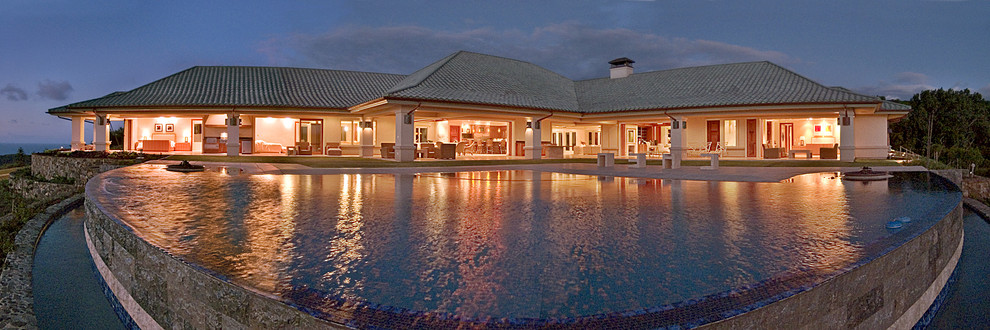 Esempio di un'ampia piscina a sfioro infinito tropicale personalizzata dietro casa con piastrelle