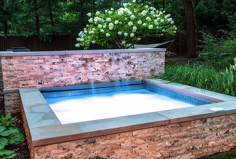 На фото: бассейн среднего размера, произвольной формы на заднем дворе в современном стиле с джакузи и покрытием из каменной брусчатки с