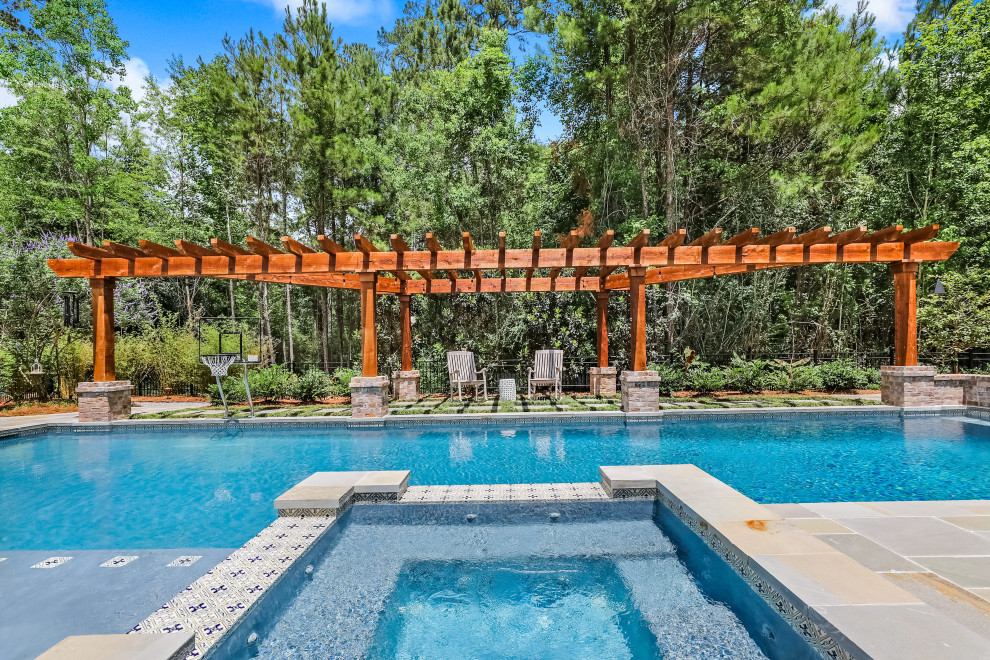 Immagine di una grande piscina country rettangolare dietro casa con fontane e pavimentazioni in pietra naturale