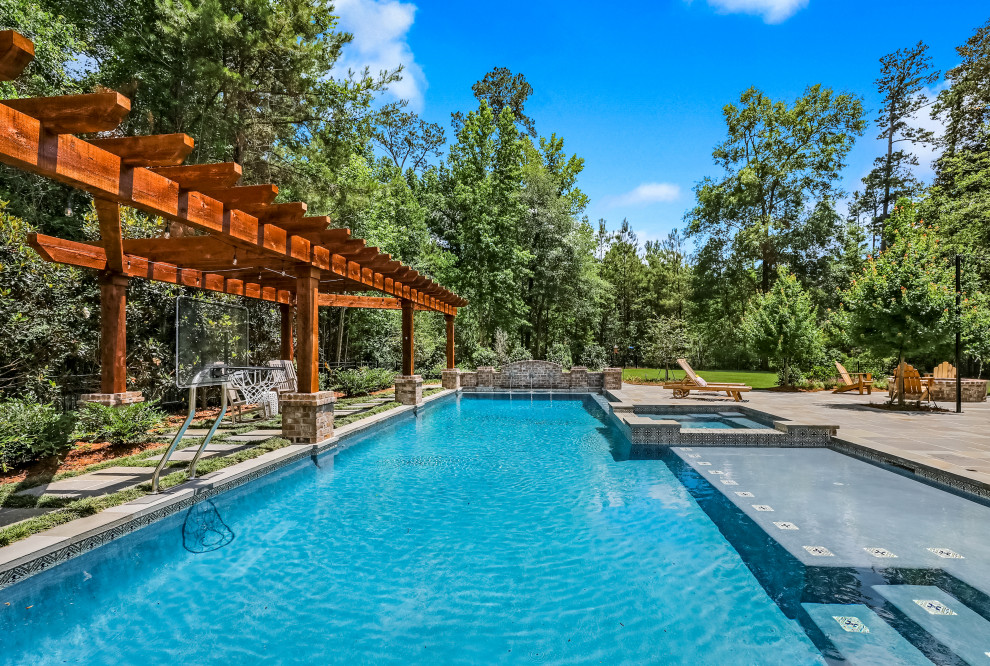 Immagine di una grande piscina country rettangolare dietro casa con fontane e pavimentazioni in pietra naturale