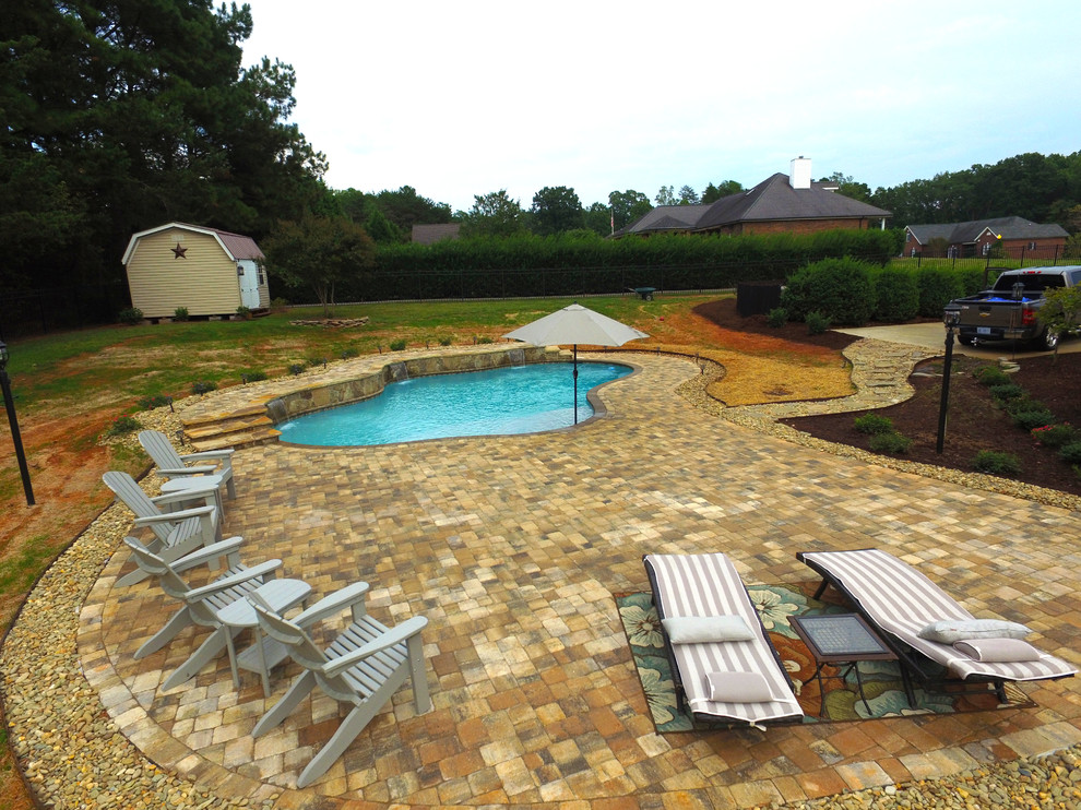 На фото: естественный бассейн среднего размера, произвольной формы на заднем дворе в современном стиле с настилом с