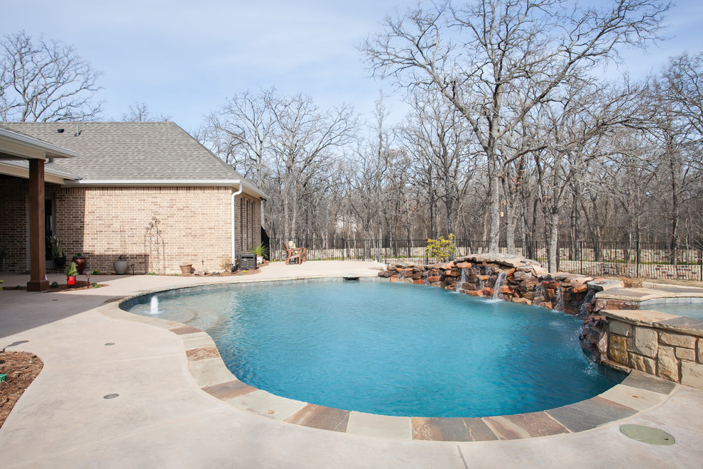 Immagine di una piscina country a "C" di medie dimensioni e dietro casa con una vasca idromassaggio e pavimentazioni in cemento