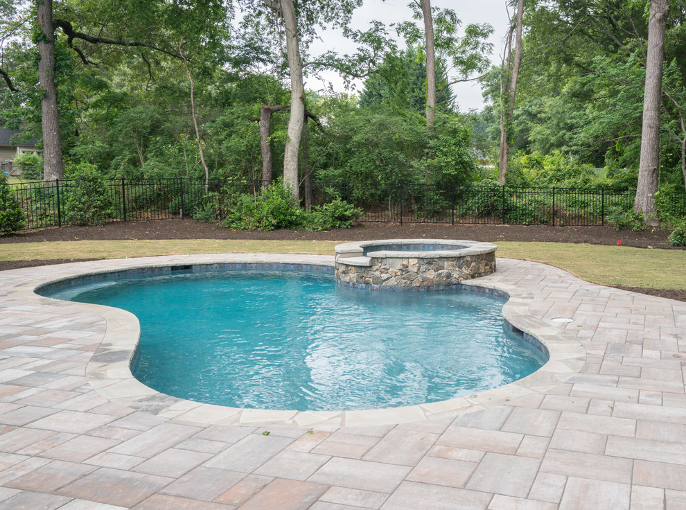 Foto di una piscina monocorsia stile americano a "C" di medie dimensioni e dietro casa con una vasca idromassaggio e piastrelle