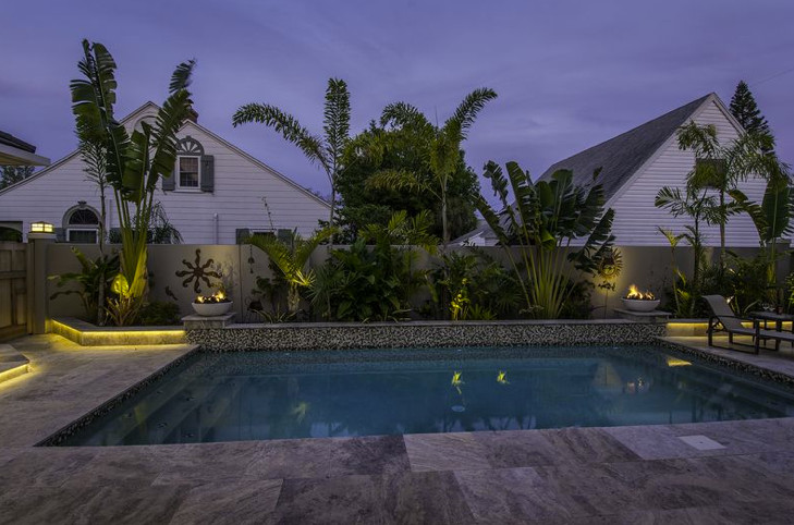 Imagen de piscina alargada de estilo americano de tamaño medio rectangular en patio trasero con adoquines de piedra natural