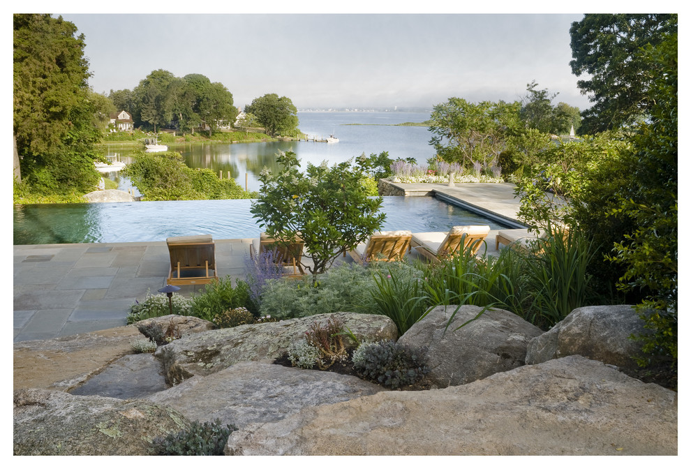 Ispirazione per una piscina a sfioro infinito stile rurale rettangolare dietro casa con pavimentazioni in pietra naturale