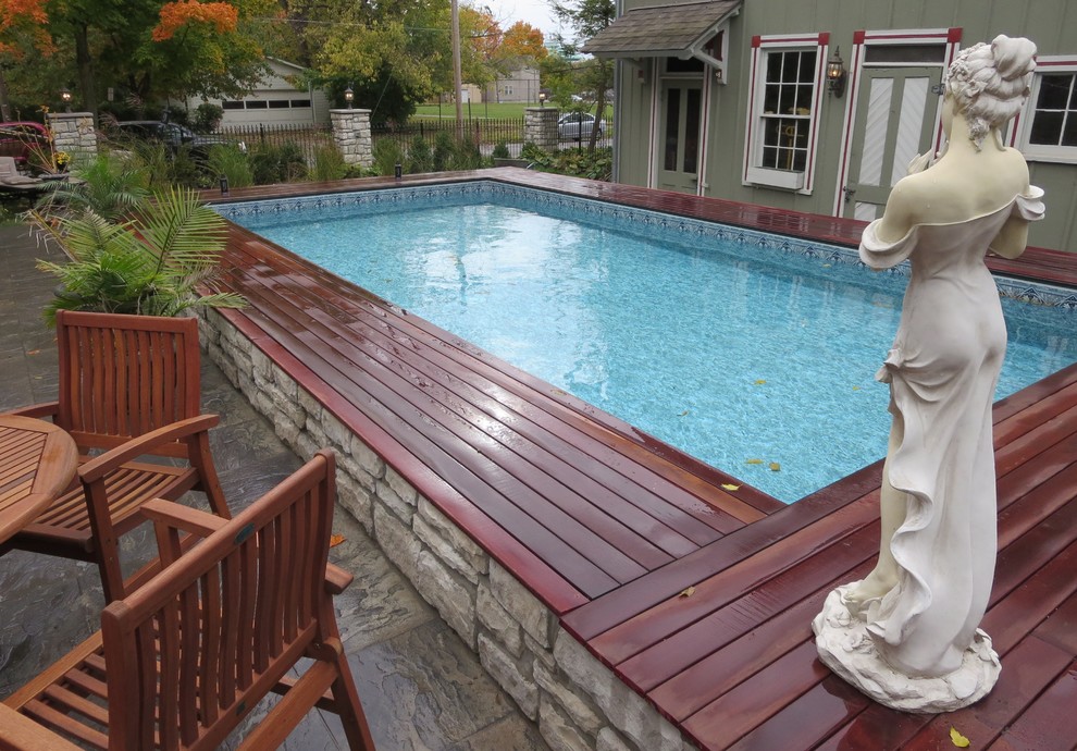 Diseño de piscina elevada tradicional renovada de tamaño medio rectangular en patio trasero con adoquines de hormigón
