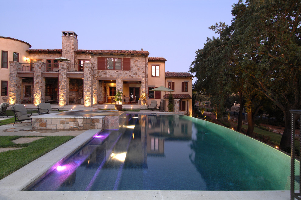 Foto de piscina con fuente infinita mediterránea grande a medida en patio lateral con adoquines de piedra natural