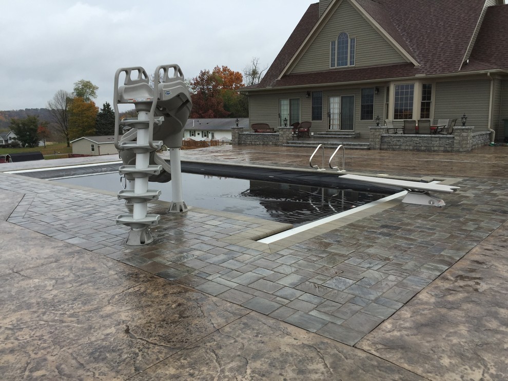 Photo of a large traditional back rectangular lengths swimming pool in Cleveland with stamped concrete and a water slide.