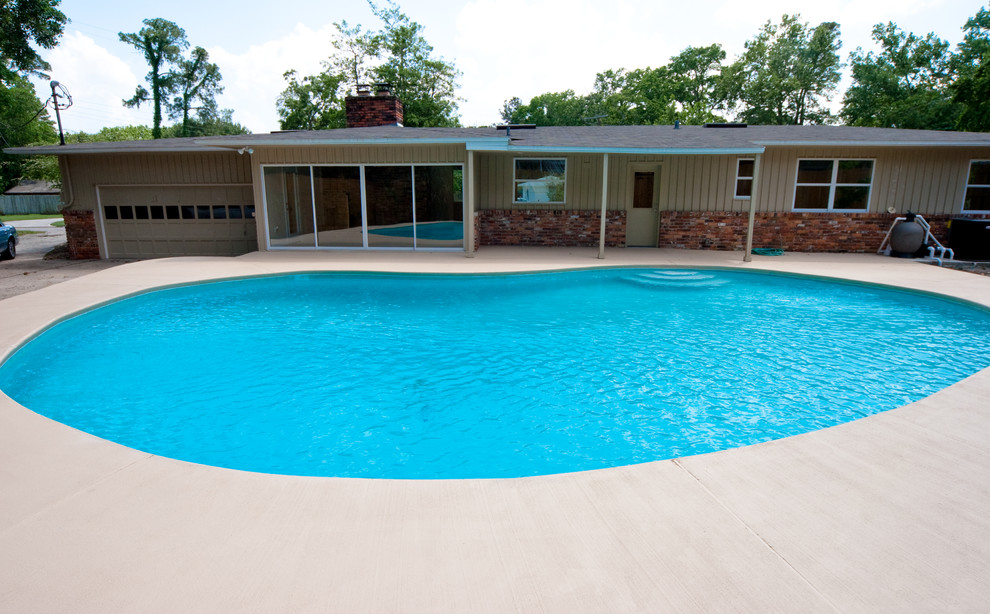 Imagen de piscina tradicional de tamaño medio tipo riñón en patio trasero con losas de hormigón