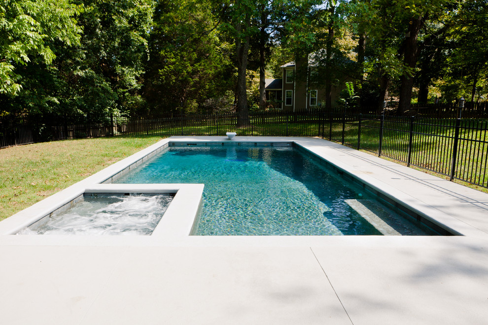 Immagine di una piscina country rettangolare dietro casa con una vasca idromassaggio e lastre di cemento