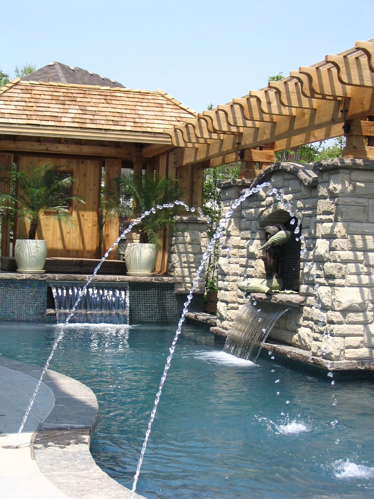 Imagen de piscina con fuente natural contemporánea en patio trasero con adoquines de piedra natural