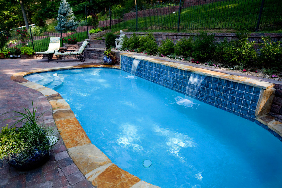 Diseño de piscina con fuente alargada tradicional grande a medida en patio trasero con adoquines de ladrillo
